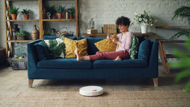 Robot vacuum twin rotating mop pads scrubbing a tiled kitchen floor during an active cleaning cycle