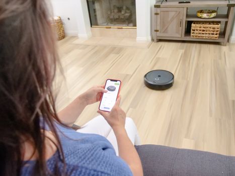 Close-up of a robot vacuum side brush and rubber roller brush cleaning hardwood flooring