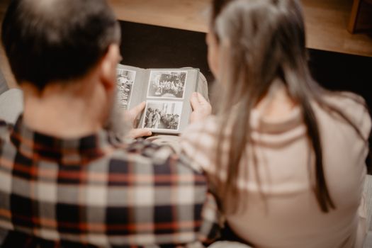 A young family sitting at a wooden dining table reviewing financial documents with a laptop open