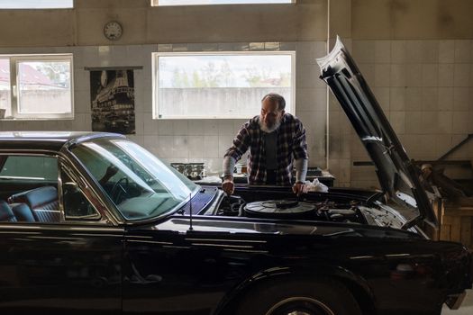 mechanic checking engine oil dipstick in modern vehicle bay
