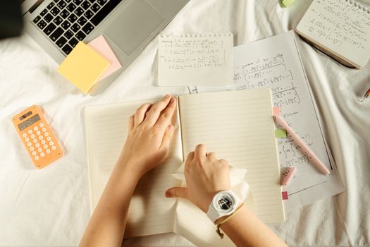 A hand holding a pen over a notebook with formulas
