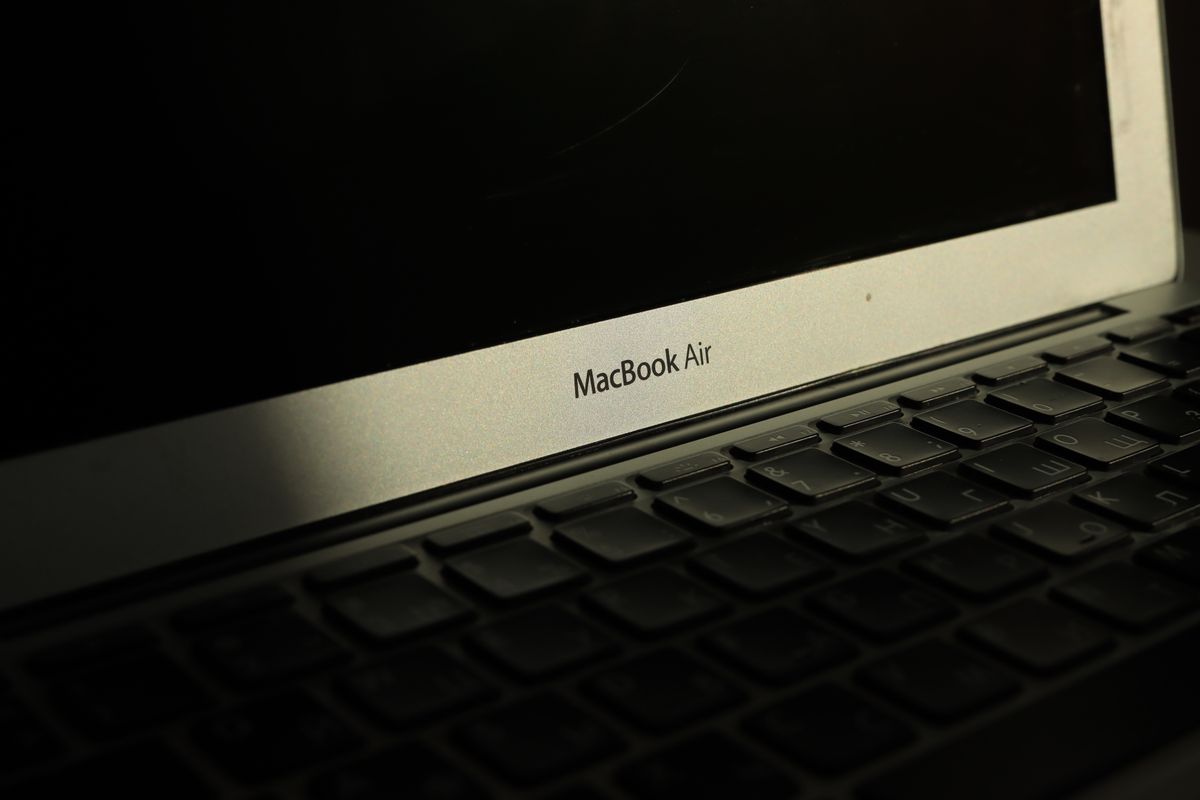 Close-up of a sunlit MacBook Air laptop showcasing its keyboard and screen with shadow effects.