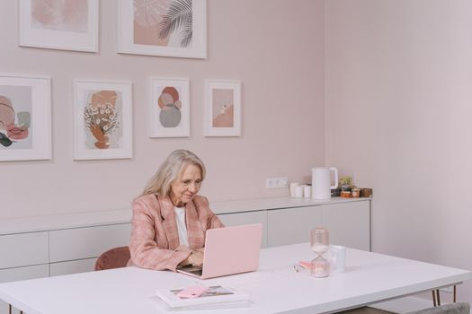 Senior citizen sitting at a clean desk analyzing colorful financial charts and documents