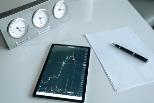 A clean, minimalist office desk with a digital tablet showing tax return progress bars and financial growth graphs.