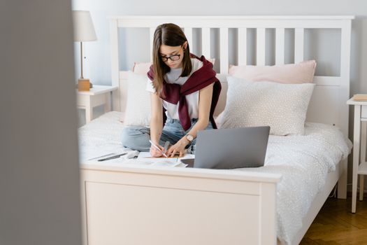 Person working on a laptop at a home office desk with financial documents