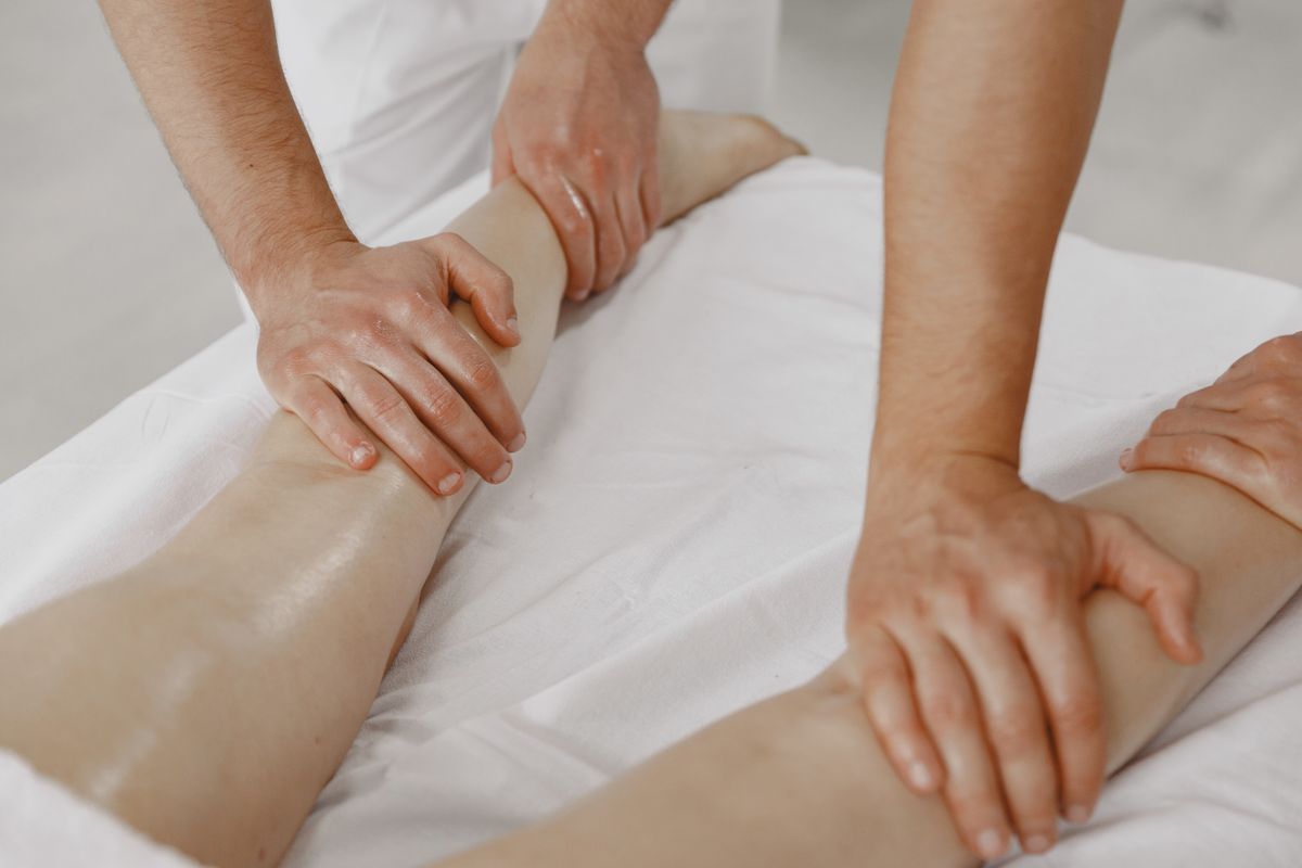 person sitting on bed holding legs in pain at night