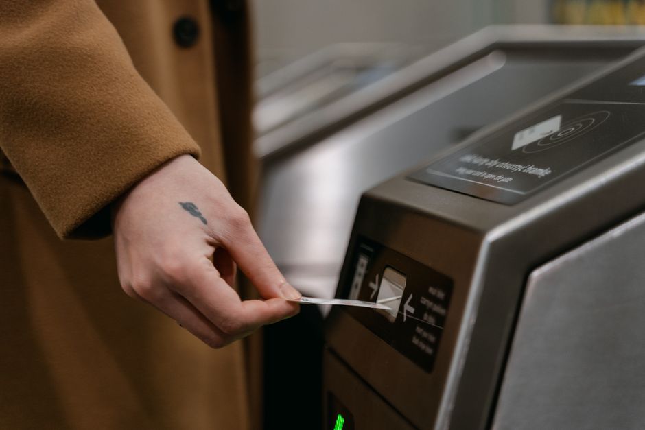 A person inserting a ticket into a turnstile at a train station, showcasing public transportation usage.