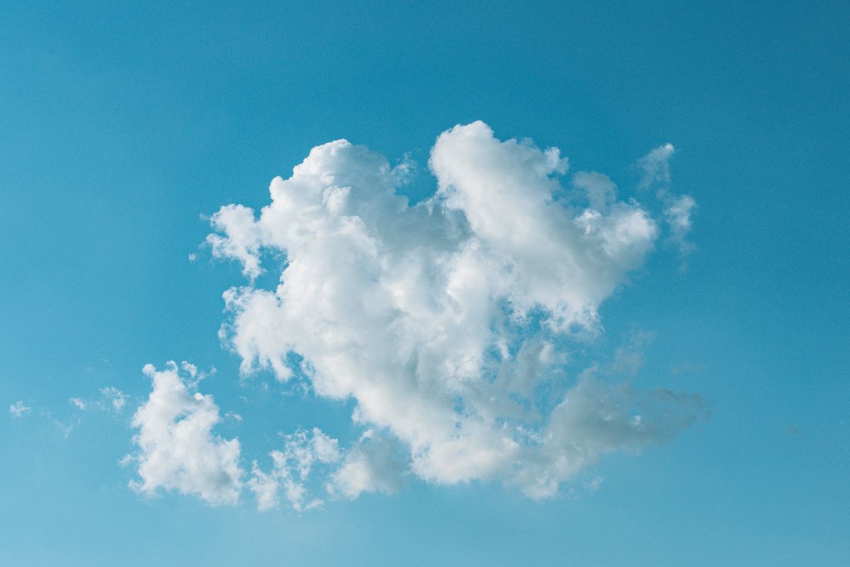A single fluffy cloud floating in a bright blue sky on a clear day.