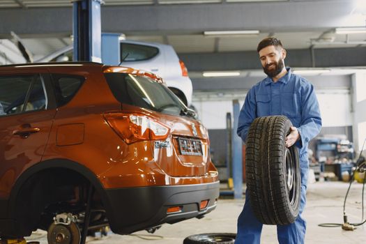 technician measuring car tire tread depth with digital gauge