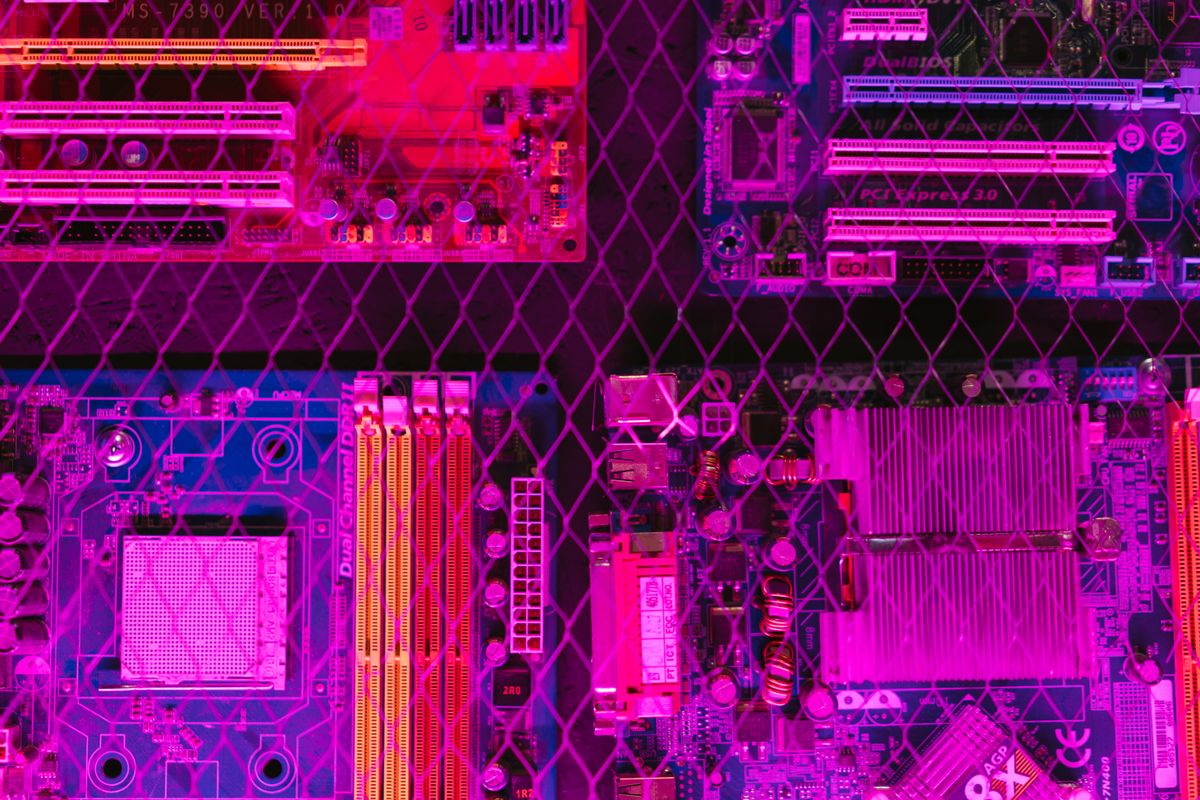 Colorful circuit boards behind a wire mesh, enhanced with pink and purple hues.
